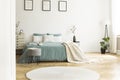 White round rug in front of green bed with blanket in bedroom in Royalty Free Stock Photo