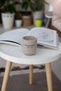 White round table with a ceramic concrete candle and a magazine, cozy interior