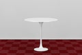 White Round Table on Red Carpet Floor against White Wall. 3d Rendering