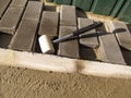 White rubber mallet close up and unfinished work on laying gray paving slabs `Brick`