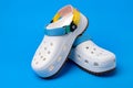White rubber sandals from Crocs with straps isolated on the blue background Royalty Free Stock Photo