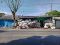 White sacks and a motorcycle on the roadside in front of a house. Roadside in Indonesia. Pile of plastic garbage sacks.