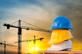 The white safety helmet at construction site with sunset silhouette and crane background Royalty Free Stock Photo