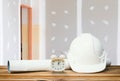White safety helmet plastic, paper roll plan blueprint alarm clock time a rest at noon on wood floor table and gypsum board wall Royalty Free Stock Photo