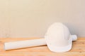 white safety helmet plastic and paper roll plan blueprint construction of engineering on wood floor table background with copy sp Royalty Free Stock Photo