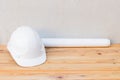 White safety helmet plastic and paper roll plan blueprint construction of engineering on wood floor Royalty Free Stock Photo