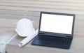 The white safety helmet put on the blueprint with laptop has white screen isolated at construction site with crane background Royalty Free Stock Photo