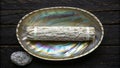 White sage bundle resting on an abalone shell bowl on a wooden surface for cleansing rituals Royalty Free Stock Photo