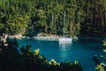 White sail boat yacht moored in the bay of Foki beach with cypress trees in background, Fiskardo, Cefalonia, Ionian Royalty Free Stock Photo