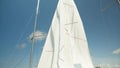 The white sail of an expensive sports yacht flutters against the blue sky in the port in sunny weather. Slow motion Royalty Free Stock Photo