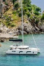 White Sailboat Floating Peacefully in the Sea of Parga, Greece, next to a Small Lush Green Island. Beautiful Turquoise Waters