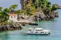 White Sailboat Floating Peacefully in the Sea of Parga, Western Greece, next to a Small Lush Green Island with a Chapel on it Royalty Free Stock Photo