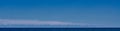 White sailboat on the horizon on the blue sea water surface. Sky panorama background Royalty Free Stock Photo