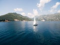 A white sailing yacht sails along the Bay of Kotor with the islands in the background near Perast in Montenegro. Royalty Free Stock Photo