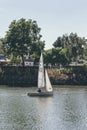 A white sails sailboat maneuvers on the River Thames near Richmond, London