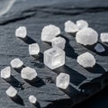 White salt crystals of various sizes rest on a dark slate surface. The crystals are Royalty Free Stock Photo