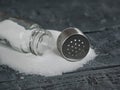 White salt poured from the open salt shaker on wooden table. Royalty Free Stock Photo