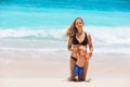 On white sand beach happy young mother with baby son