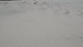 White sand dune with ripples and wisps of sand being blown off the crest Royalty Free Stock Photo