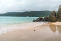 White sand, overcast skies, granite stones and turquoise sea at Fairyland Beach, Seychelles Africa.