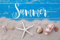 White sand star fish and shells with summer text on blue wooden Royalty Free Stock Photo