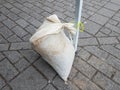 White sandbag on metal pole and grey bricks