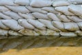 White sandbags for flood defense and it's reflection brown water Royalty Free Stock Photo