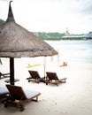 White sandy beach with empty lounge chair covered by beach umbrella thatched palm leaves, on quite private island shoreline of