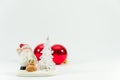 White Santa Claus figurine, two red Christmas tree balls in the background. Royalty Free Stock Photo