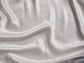 White satin background with folds and shadows. Light shiny rippled silk texture website advertisement design