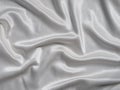 White satin background with folds and shadows. Light shiny rippled silk texture website advertisement design