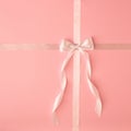 White satin ribbon bow on pink pastel background. Top view. Copy space.