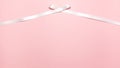 White satin ribbon bow at the top on pink background with copy space from above Royalty Free Stock Photo