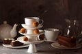 White saucer pyramid with cup of tea on top decorated with chocolate truffles on surved dessert table on dark background. Creative