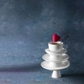 White saucer pyramid with cup of tea on top and flying red hearts candy over it. Dark background. Creative concept, love,