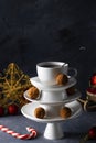 White saucer pyramid with cup of tea on top, like Christmas tree with decorated with sweet chocolate truffles, dark background