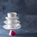 White saucer pyramid with cup on top and one red heart candy on it Dark background. Creative concept, love, relations, gift,