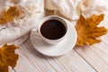White scarf, cup of coffee and dry yellow leaves on a wooden table. Autumn mood, copy space Royalty Free Stock Photo