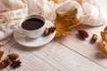 White scarf, cup of coffee and dry yellow leaves on a wooden table. Autumn mood, copy space Royalty Free Stock Photo