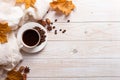 White scarf, a cup of coffee with scattered coffee beans, dry yellow leaves on a wooden table. Autumn mood, copy space Royalty Free Stock Photo