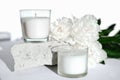 white scented soy wax candles on a natural stone and peony flowers. floral fragrance for cozy home. aromatherapy and