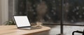 A white-screen laptop computer mockup and a coffee cup on a wooden table in a modern meeting room Royalty Free Stock Photo