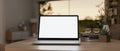 A white-screen laptop computer mockup on a wooden table in a beautiful cosy living room Royalty Free Stock Photo