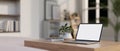 A white-screen laptop computer mockup on a wooden table in a modern white living room Royalty Free Stock Photo