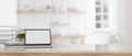 A white screen laptop mockup on a tabletop with a blurred modern white room in the background Royalty Free Stock Photo