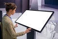 Woman using interactive empty white touchscreen display kiosk at exhibition Royalty Free Stock Photo