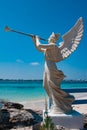 White sculpture of an angel holding trumpet on the tropical island.