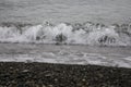 White sea foam on a rocky pebble beach, high tide