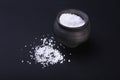 White sea salt in clay bowl on a black background. Selective focus. Royalty Free Stock Photo