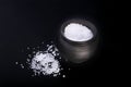 White sea salt in clay bowl isolated on a black background. Selective focus. Royalty Free Stock Photo